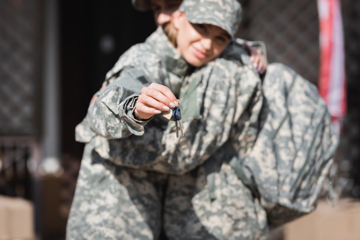 Keys with blurred military wife and husband hugging on background.