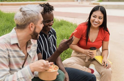 Diverse people having fun eating take away food outdoor in the city.