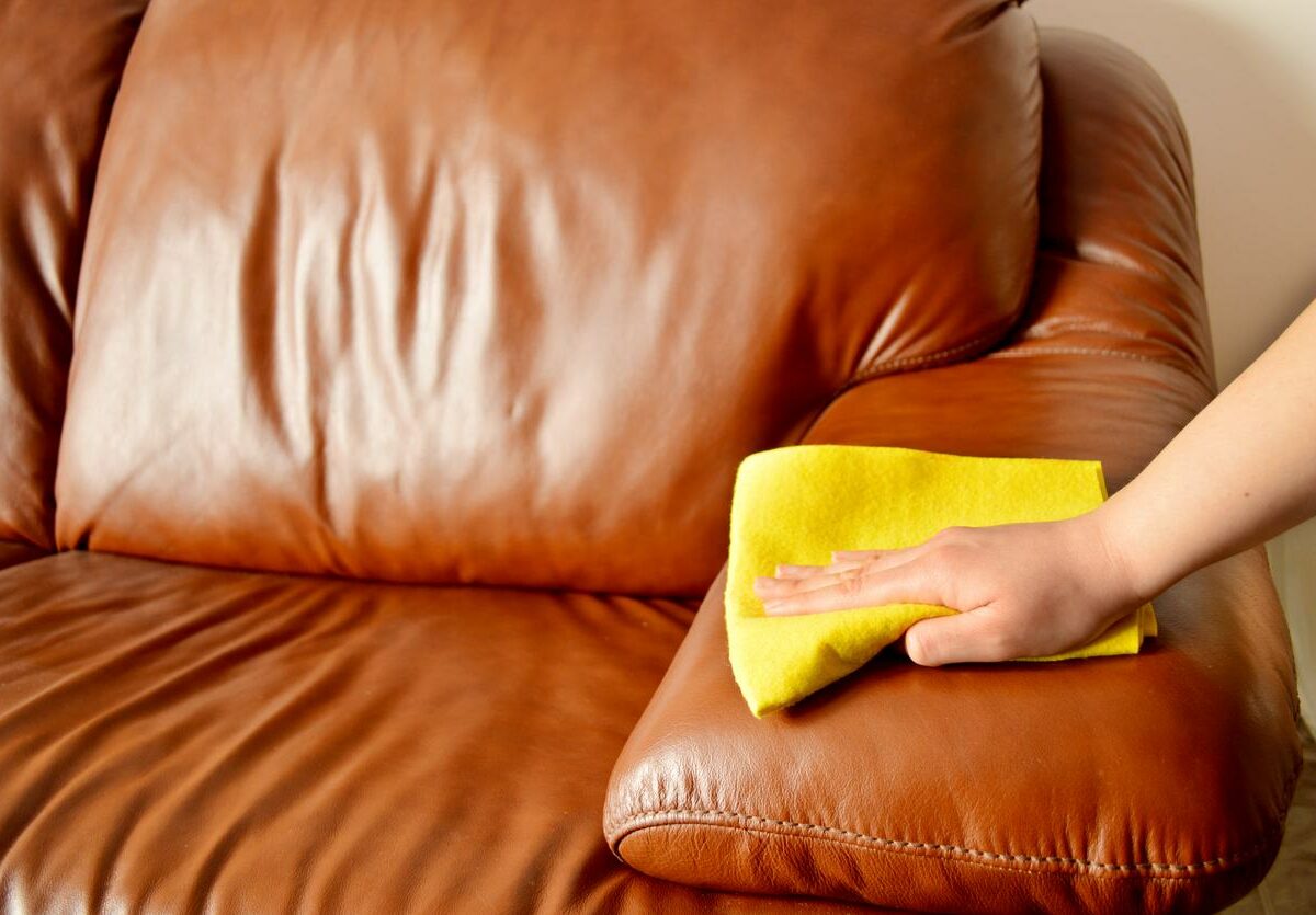 Person wiping down a leather couch