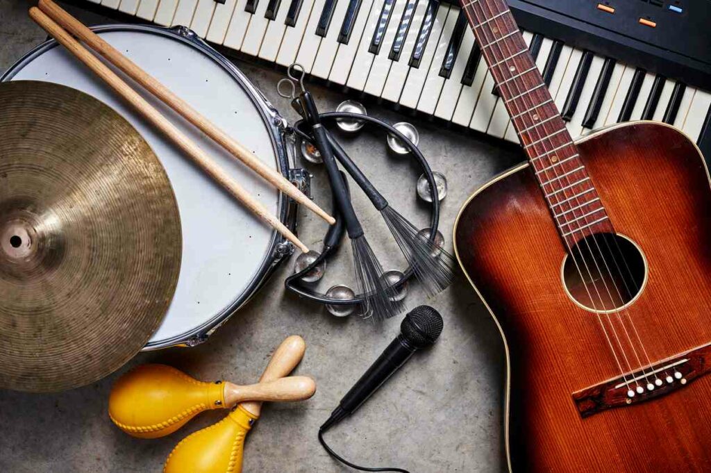 Instruments stacked together including drums, guitar, tambourine, and piano