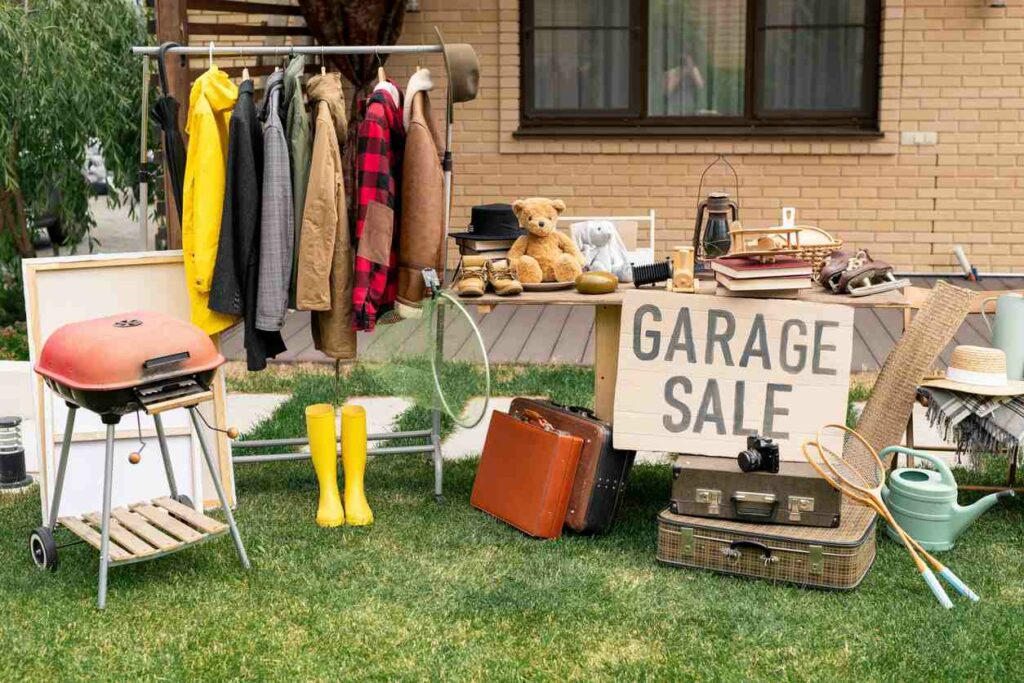 Assorted items on a grass lawn with a sign that reads “garage sale”