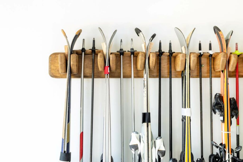 A wooden rack on the wall holding skis and ski poles
