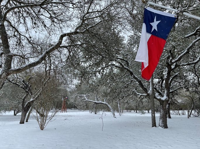 Snow covering Texas with a view of the Texan flag hanging.