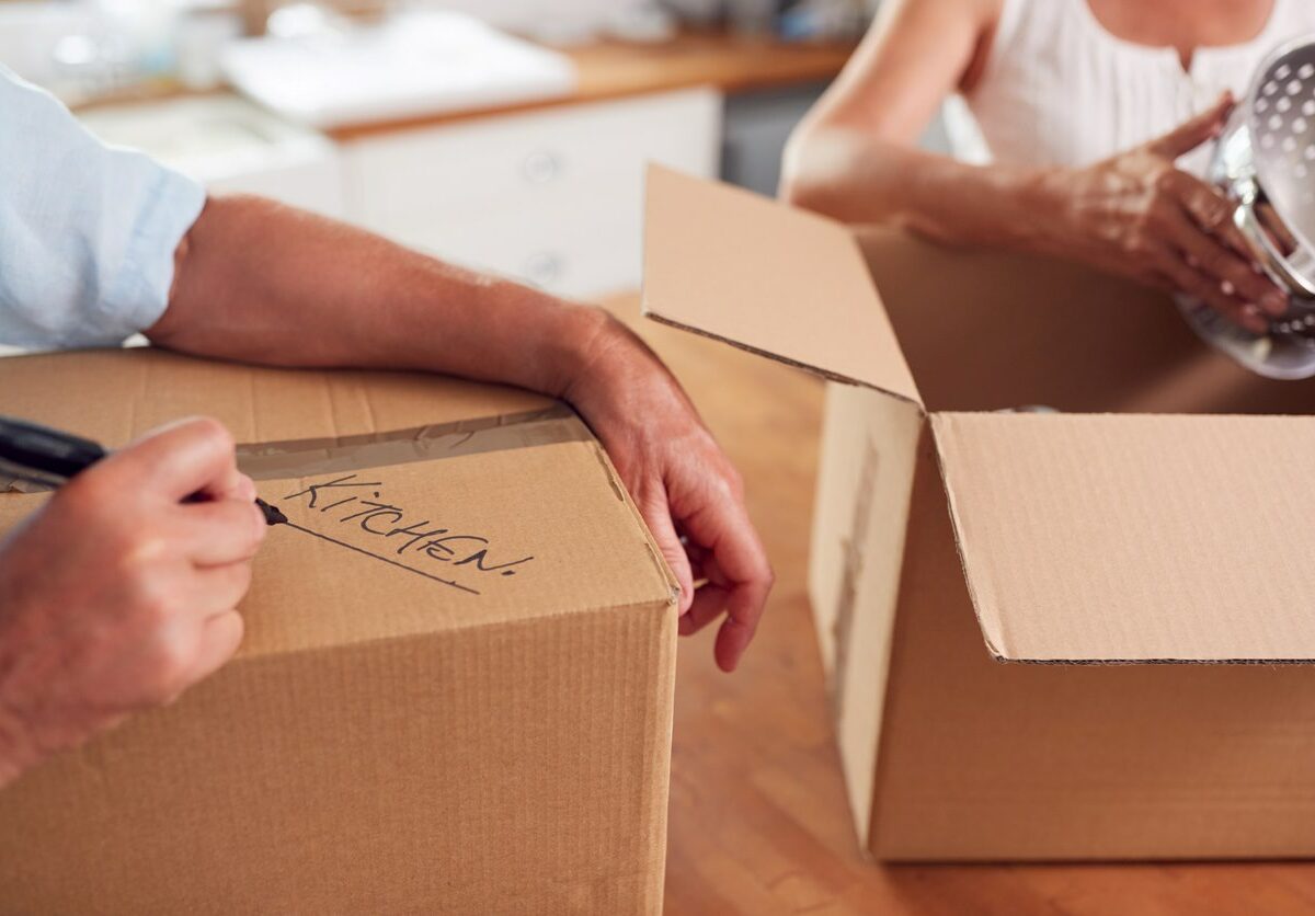 A man and woman label boxes as they pack items to put in their self storage unit.