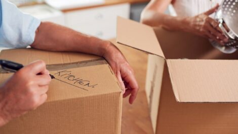 A man and woman label boxes as they pack items to put in their self storage unit.