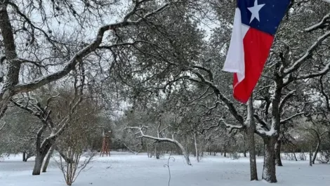 Snow covering Texas with a view of the Texan flag hanging.