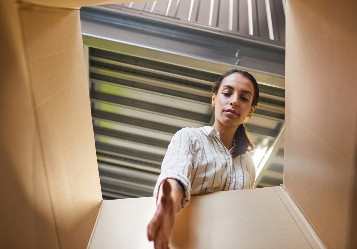 A young woman reaching into a box while loading a storage unit.