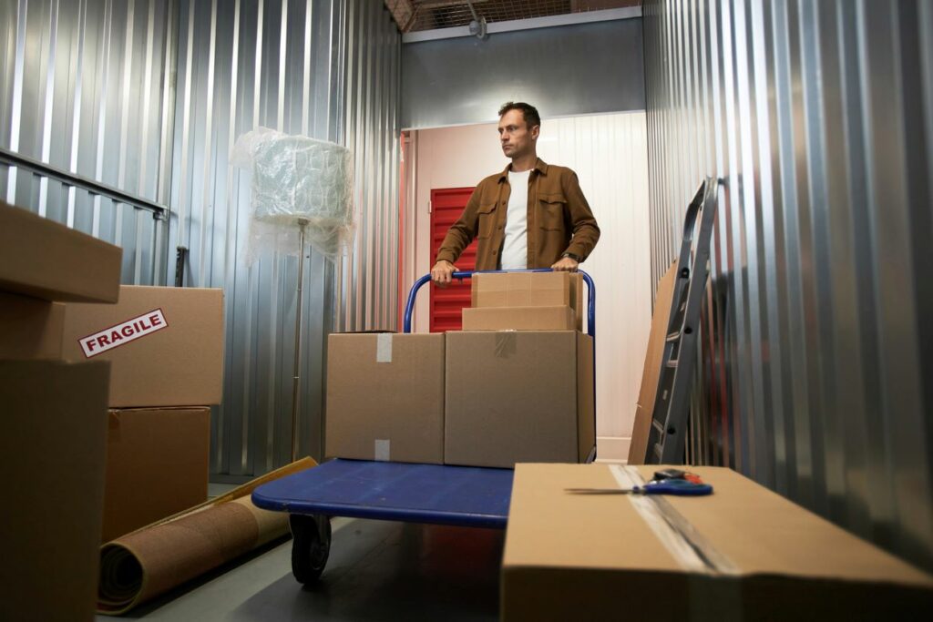 Man pushing a cart into a storage unit. 