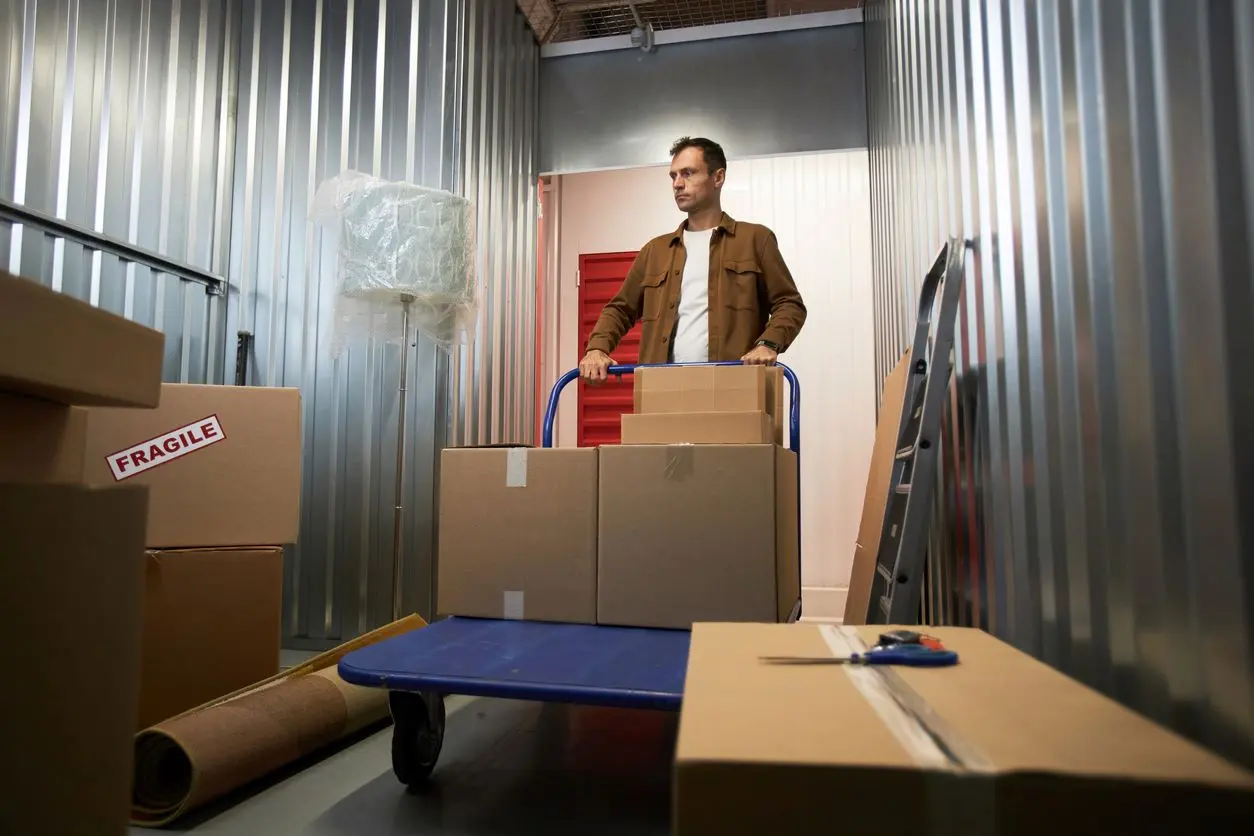 Man pushing a cart into a storage unit.