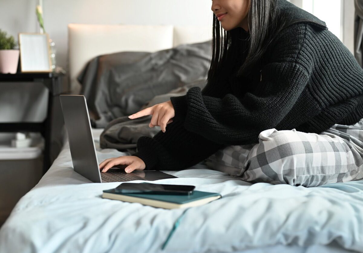 A college student working on homework in bed.