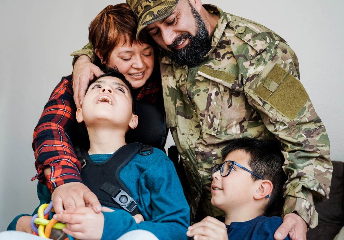 A military dad in uniform hugs his family.