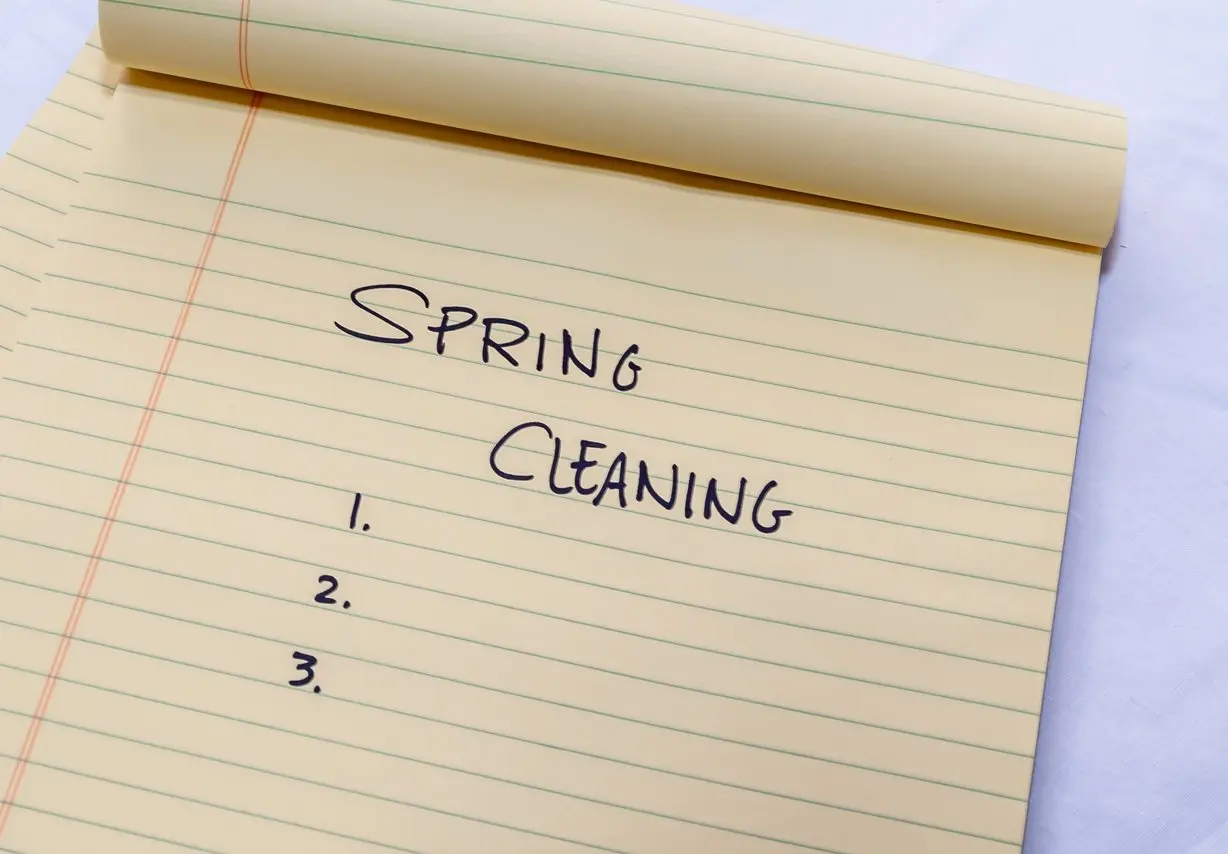 A yellow notepad with "spring cleaning" written at the top and a numbered list below it. 
