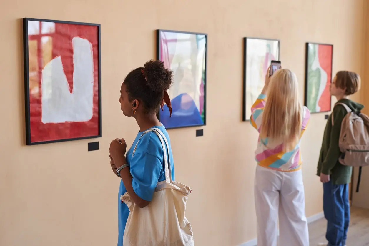 Three people viewing colorful abstract art in a modern gallery. 