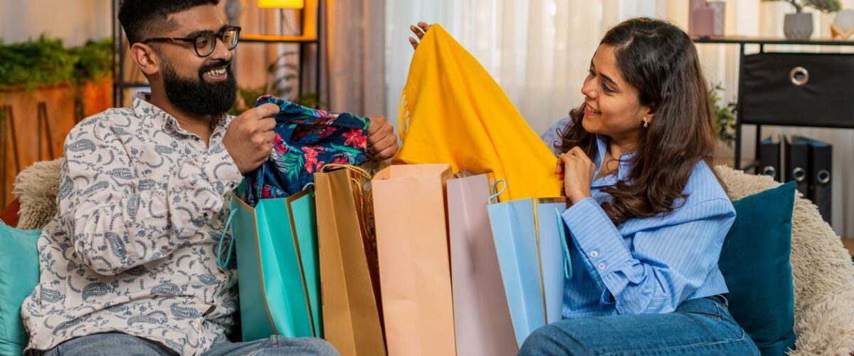 A man and woman opening Black Friday shopping bags at home.