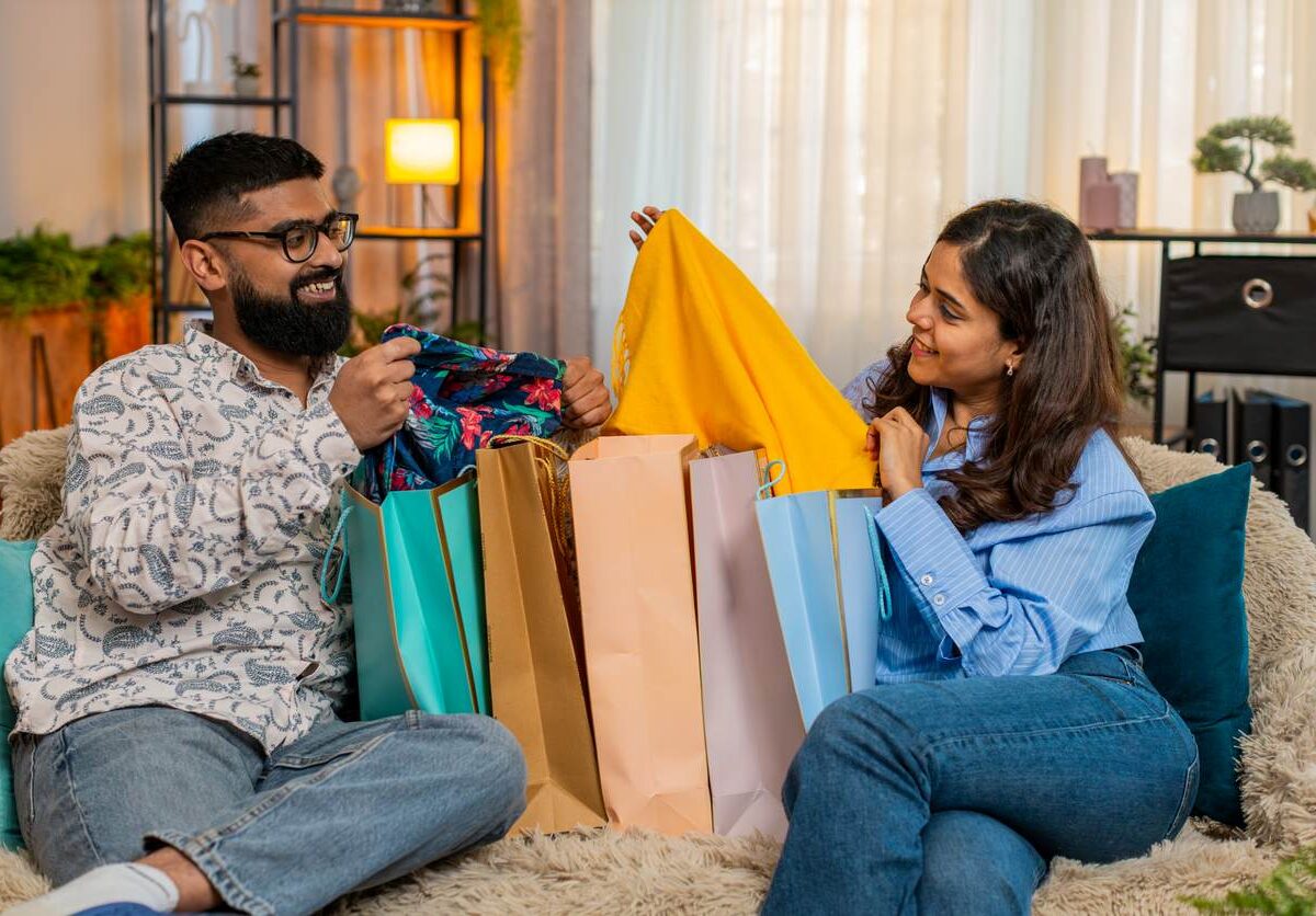 A man and woman opening Black Friday shopping bags at home.