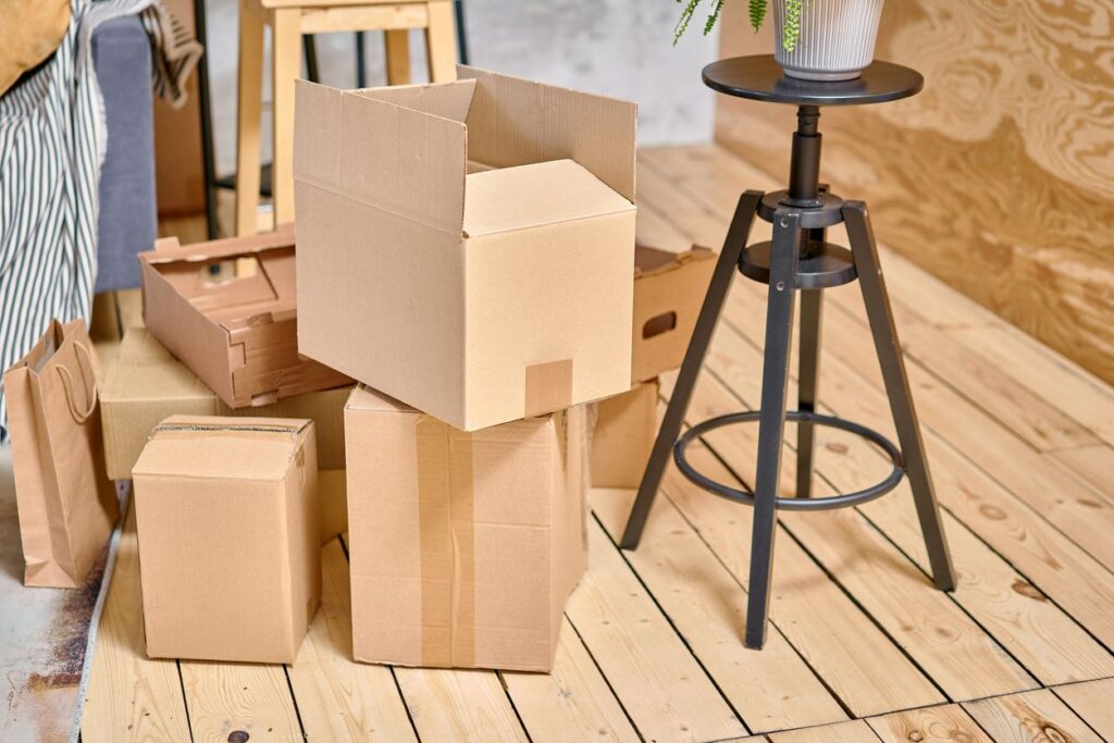 Stacked cardboard boxes in a room with wooden flooring, showing packing and storage items ready to be organized.